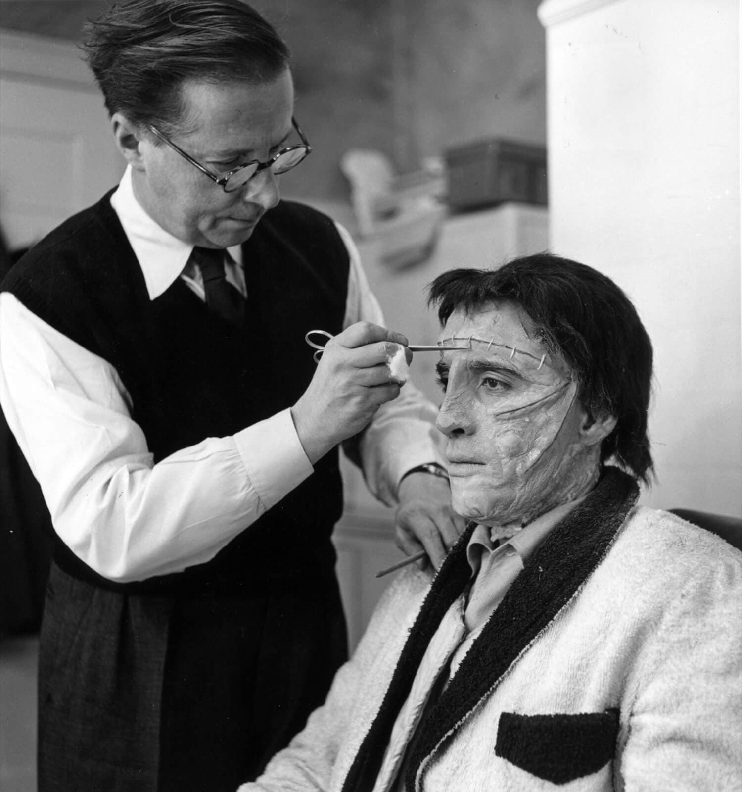Make-up artist, Phil Leakey, prepares Frankenstein for his appearance in The Curse of Frankenstein, 1957.
